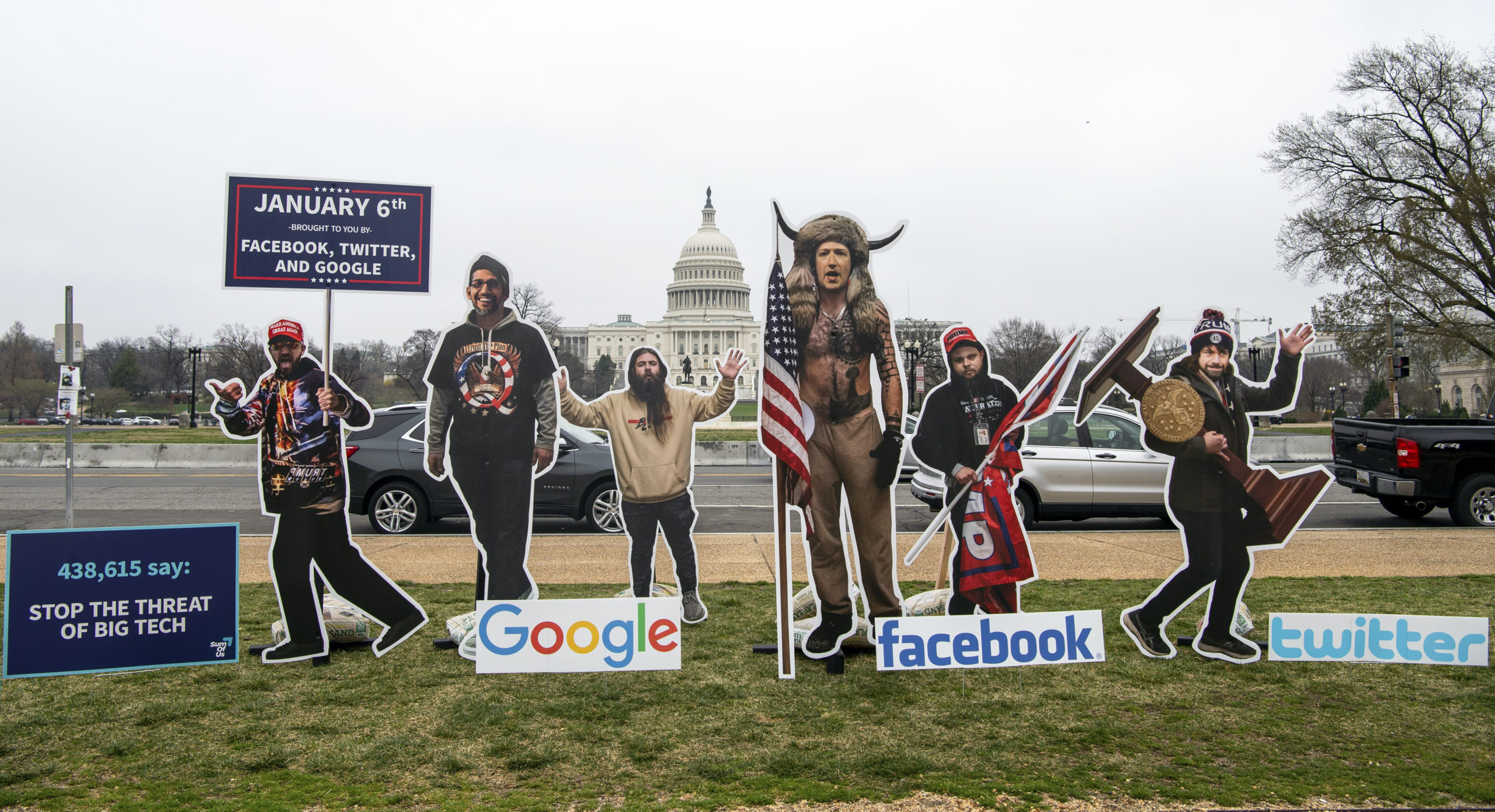 Cardboard cutouts of tech CEOs in QAnon gear, placed outside Congress by anti-Q protestors in March 2021, highlight their platforms' role in spreading theories that led to the Jan. 6 insurrection.