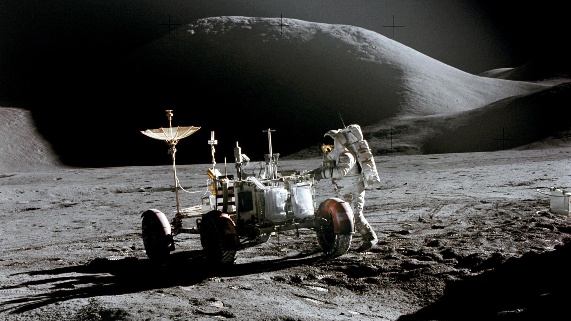 Apollo 15 astronaut James Irwin is pictured on the moon beside the first Lunar Roving Vehicle, captured by David Scott. Mount Hadley looms in the background.