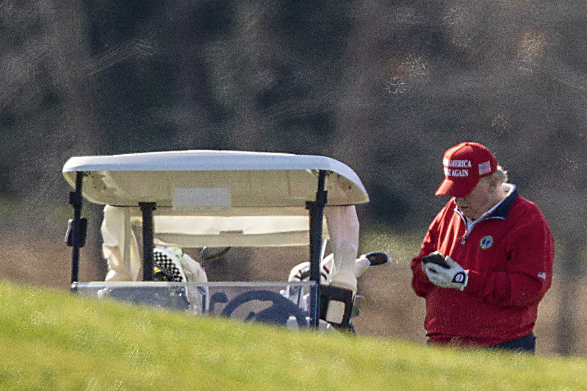 Former U.S. President Donald Trump looks at his phone but absolutely not at Twitter or Facebook, where he is now banned, as he golfs at Trump National Golf Club.