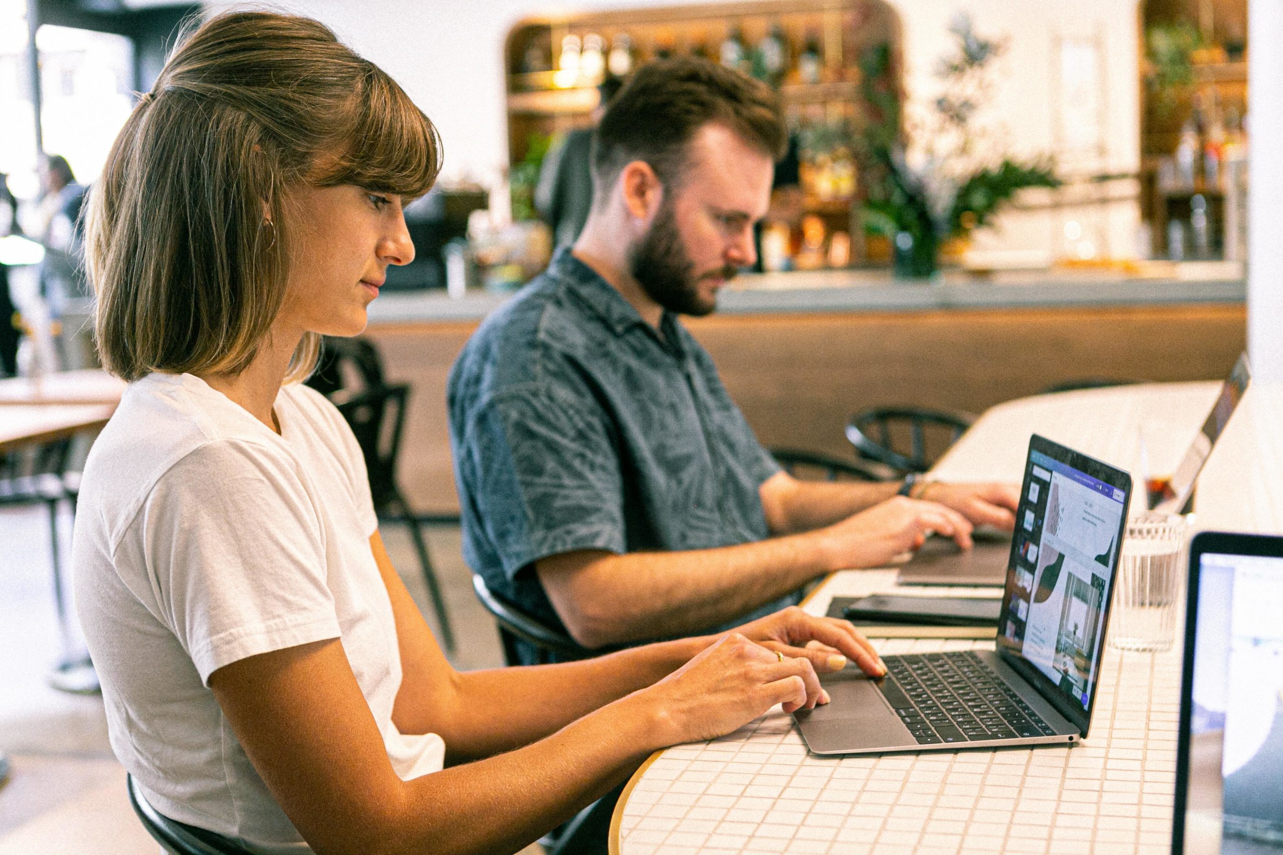 Outsource your social media, newsletters, and other work to this handy AI tool. Pictured:  A man and a woman type on laptops.