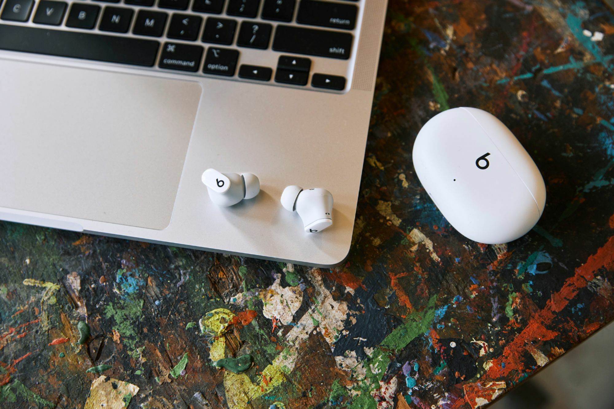 a pair of white beats studio buds sitting on a macbook next to their matching case