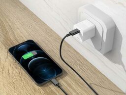 a usb-c charger plugged into an outlet on the wall charging on iphone on the floor