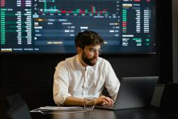 man on laptop with blockchain programming on the screen behind him