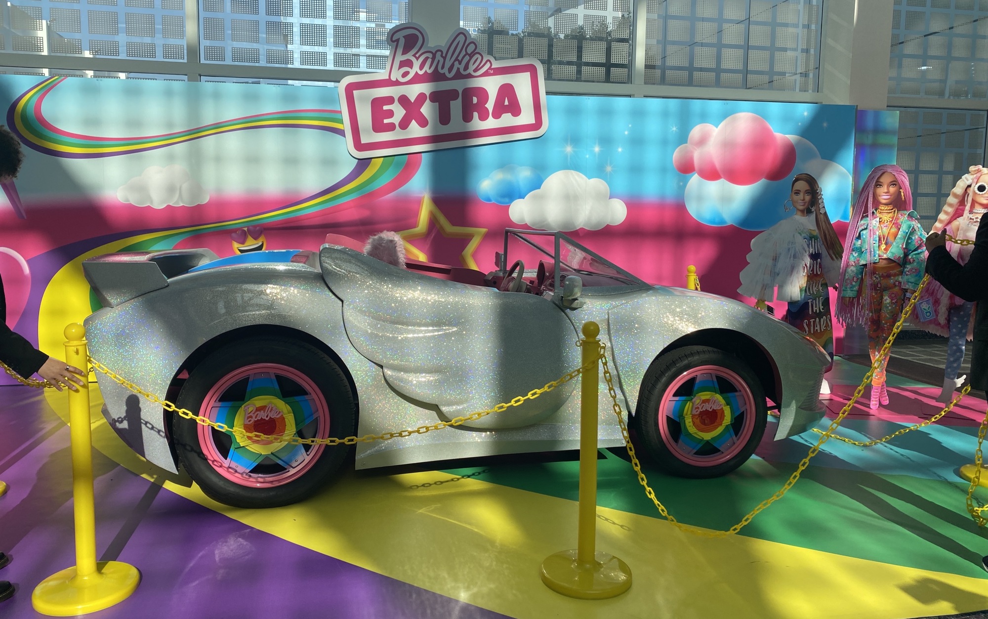 The Barbie Extra car displayed at the LA Auto Show. It has a glitter paint job and rainbow hubcaps.