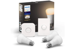 three white light bulbs, a philips hue hub, and a smart button next to their box