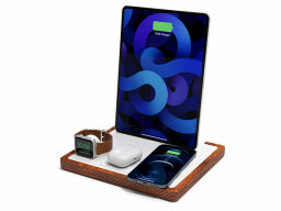 Tablet, phone, earphone case, and watch on wood and white charging station