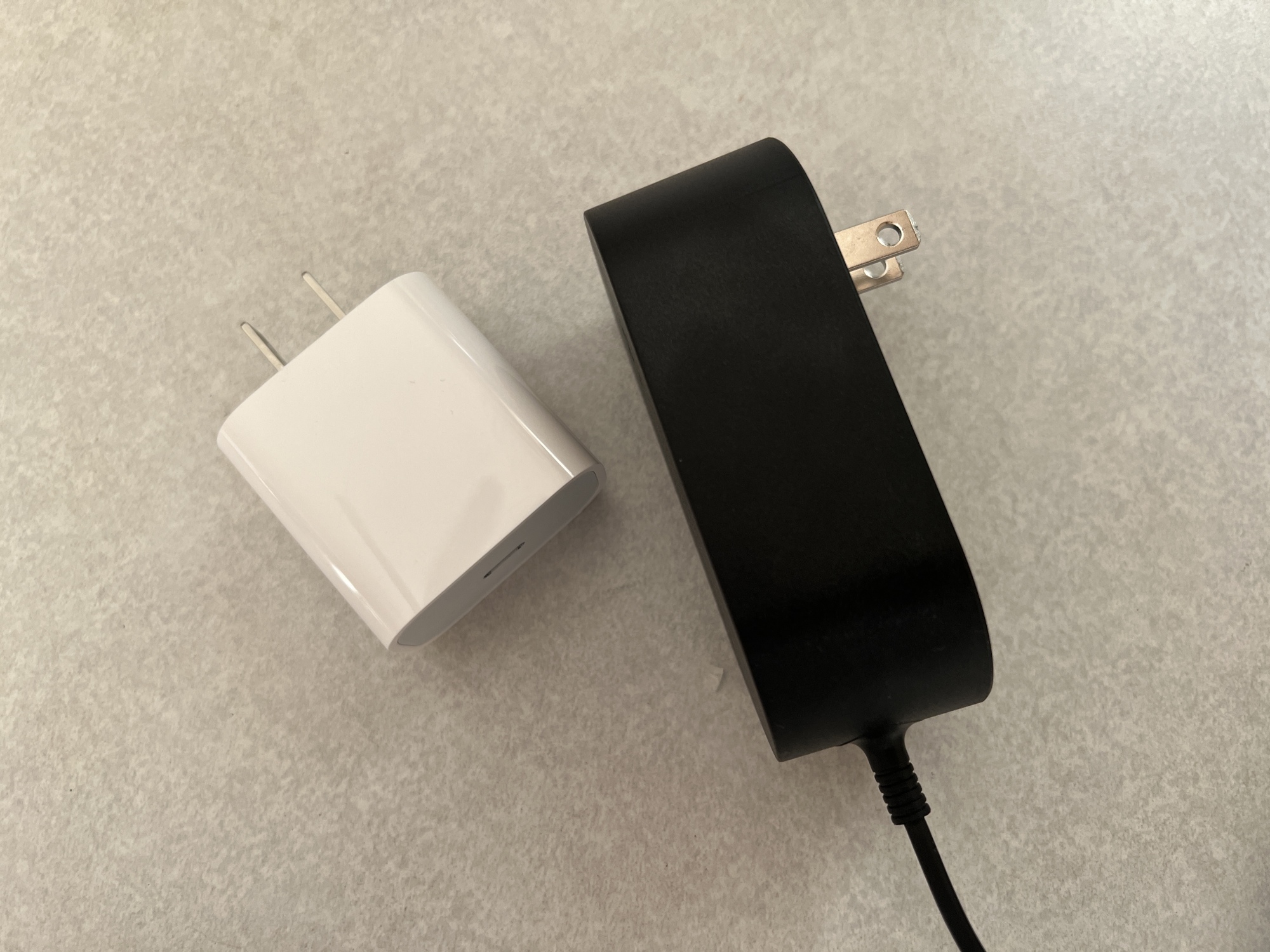 White 20 watt USB-C adaptor from Apple on the left, black attached 15 watt adaptor from Belkin on the right.