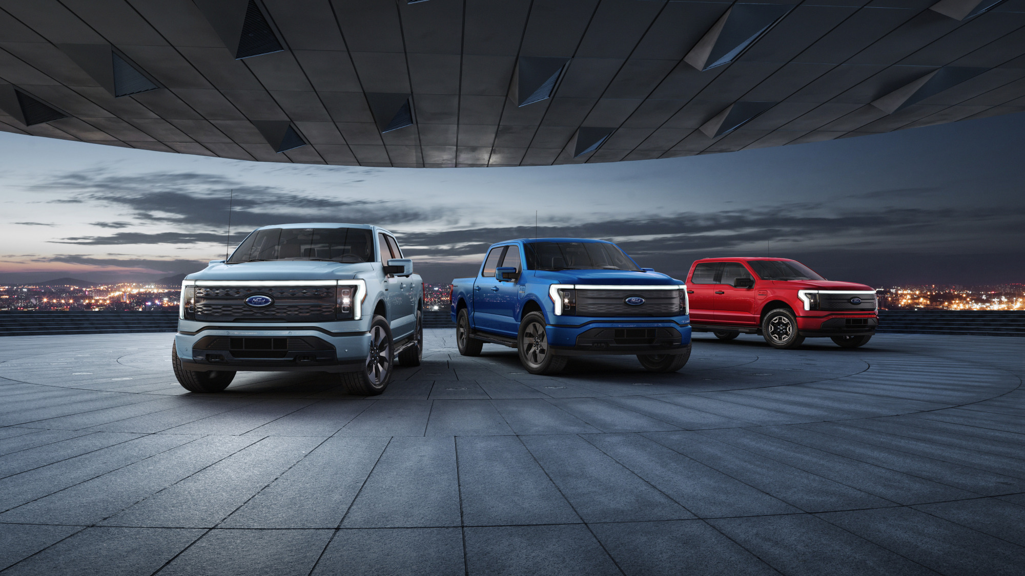 A row of F-150 Lightning pickup trucks in silver, blue, and red.