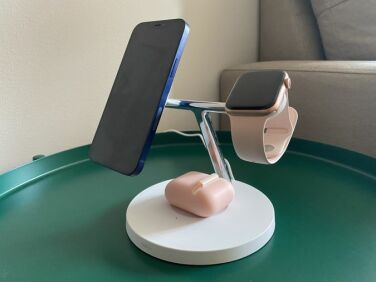 Last year's Belkin charger, white in color and with an aluminum T-bar design. Holding an iPhone 12 at a floating angle on the left MagSafe pad, the Apple Watch on the right pad, and AirPods on the bottom base.