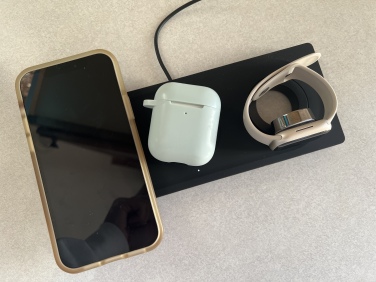 Black Belkin 3-in-1 charging pad, holding an iPhone, AirPods. and Apple Watch.