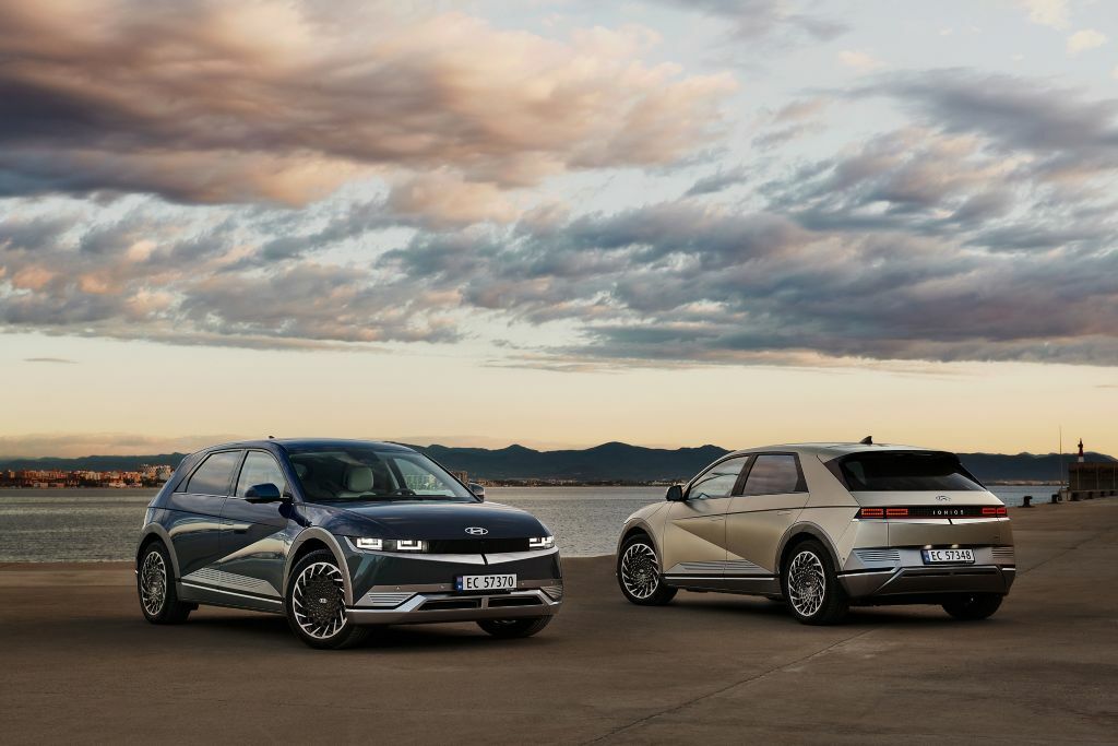 Two cars facing end to end with a cloudy sky overhead.