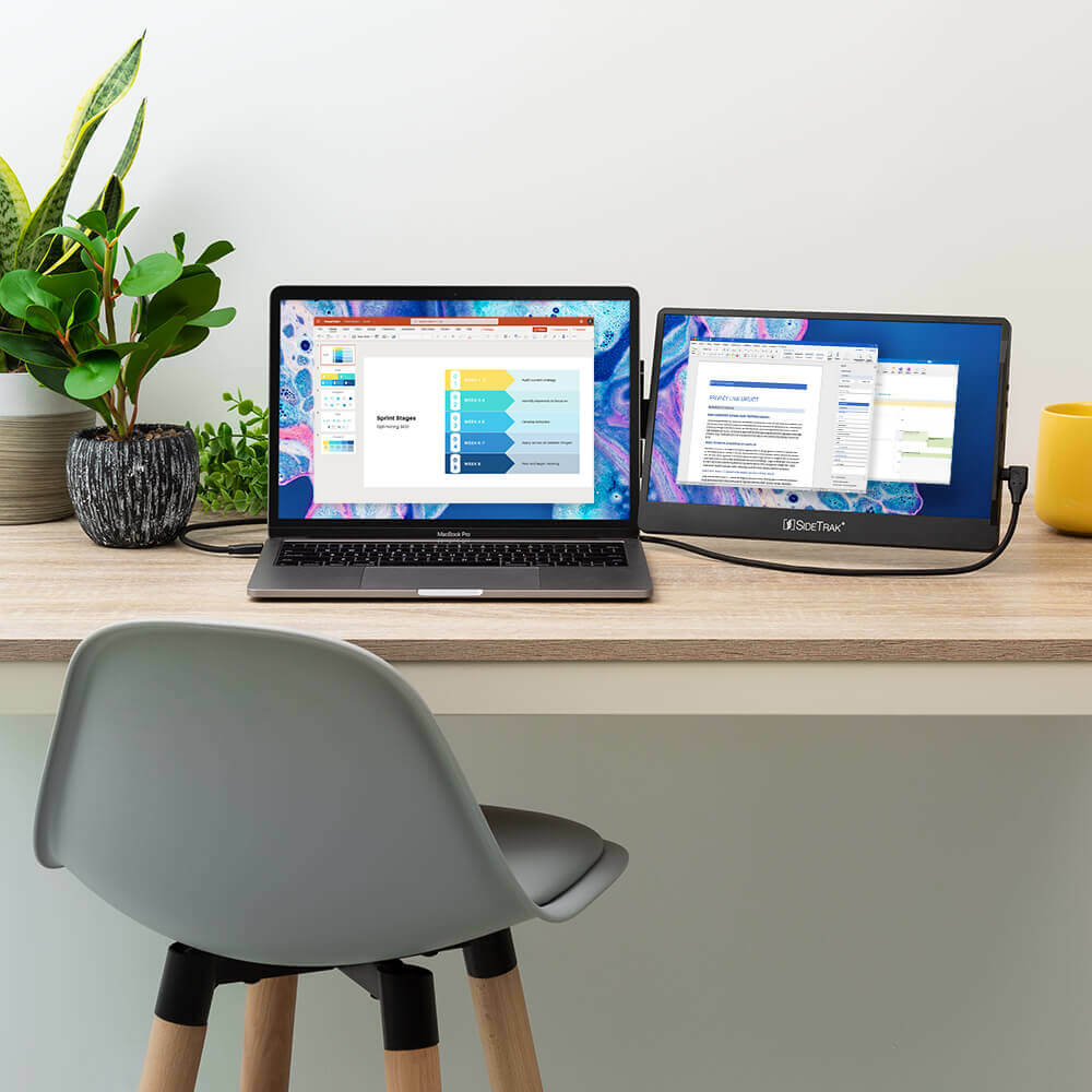 An empty chair at a desk with a laptop and a Sidetrak Swivel monitor.