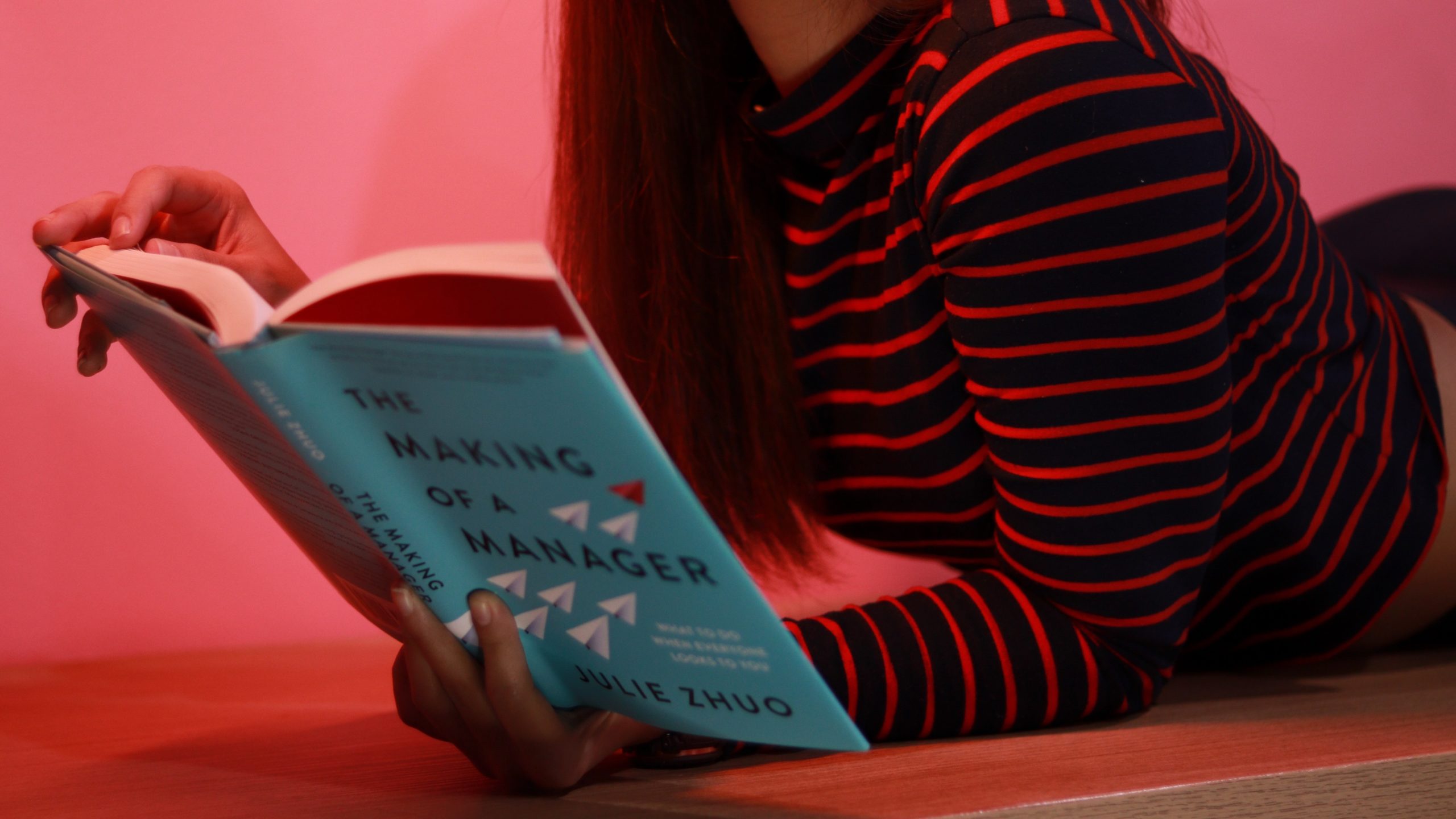 Person lying down on stomach holding green book