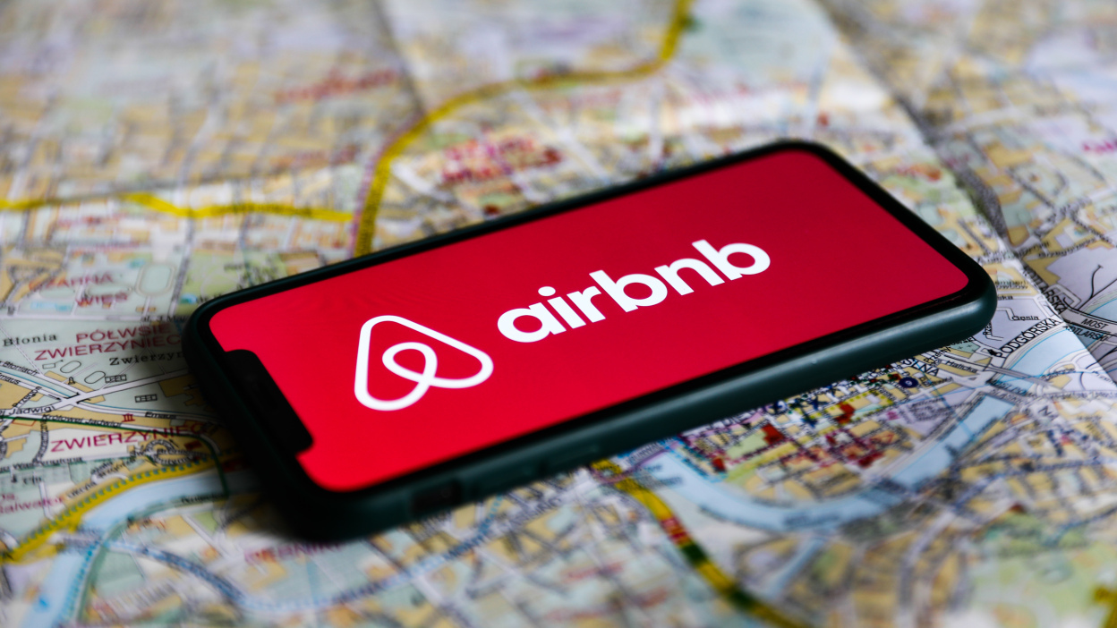A photograph of an iPhone with the AirBnb logo on it, against a map.