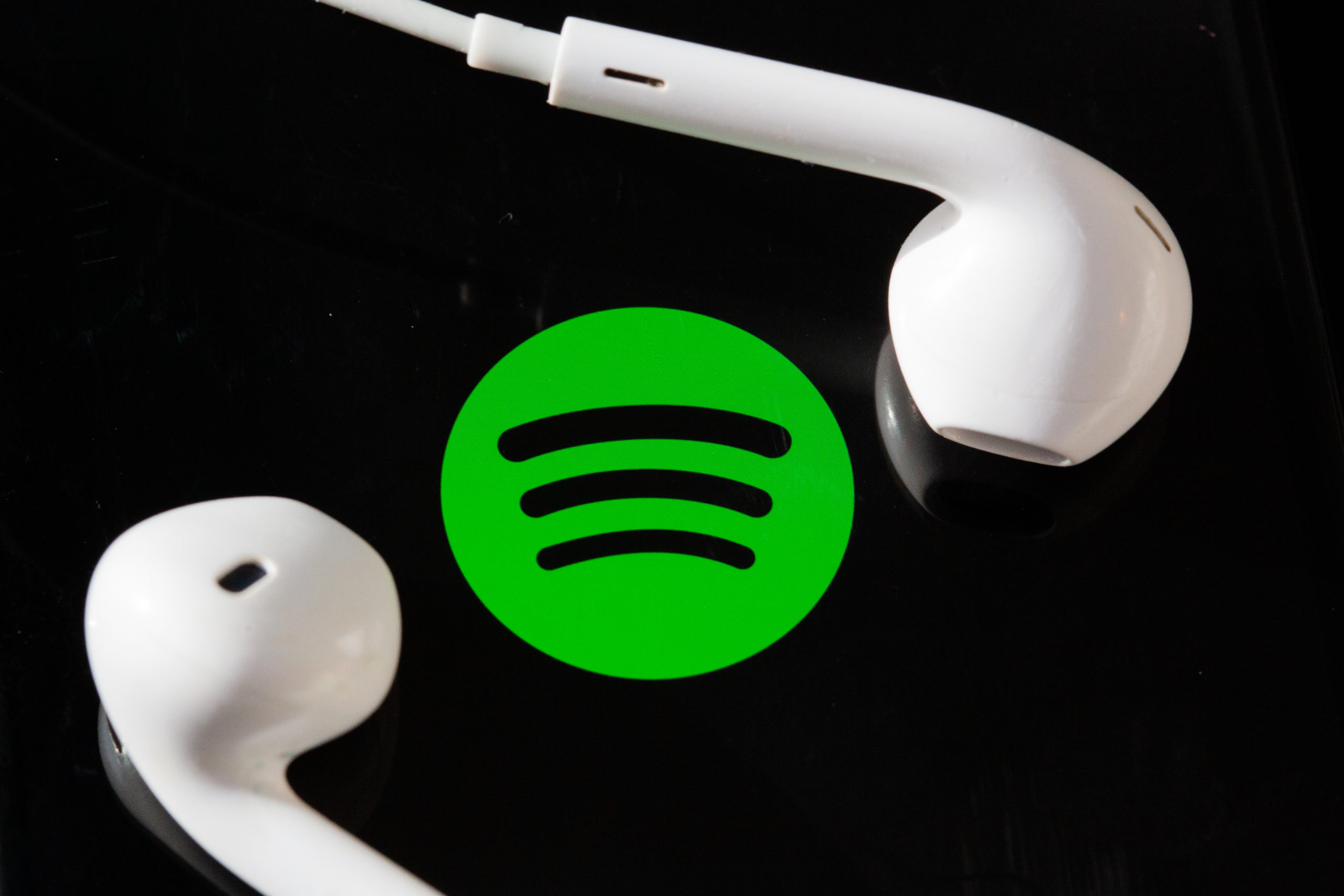 Spotify icon surrounded by two headphones. 