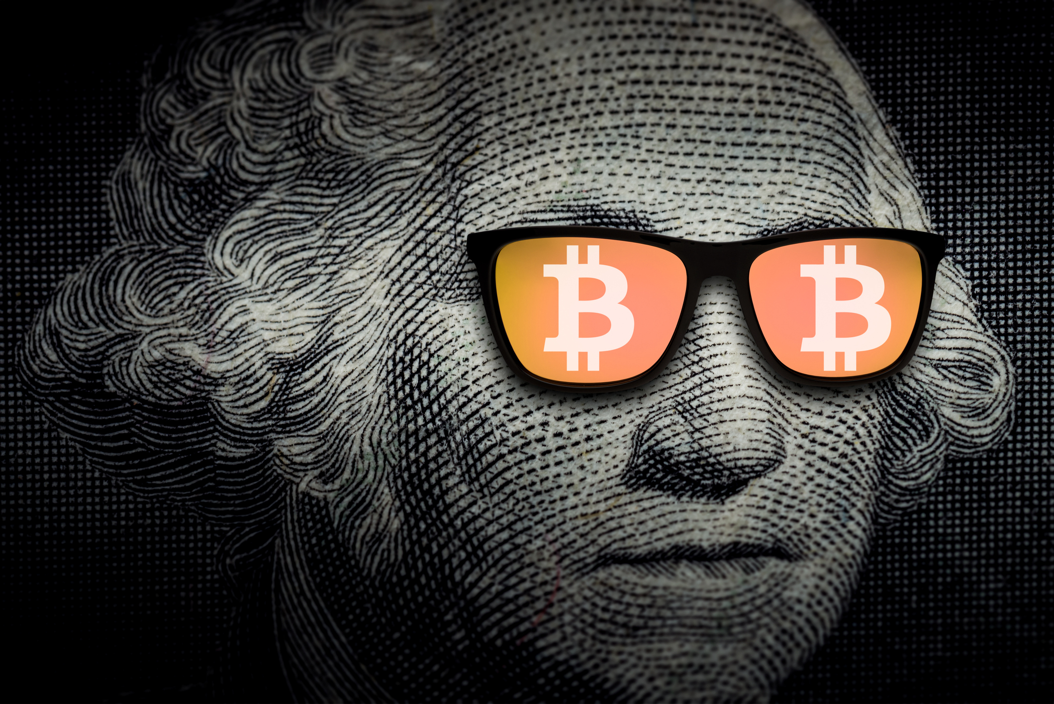 A close up of George Washington, on the U.S. dollar bill, wearing sunglasses with the Bitcoin logo superimposed over the lenses. 