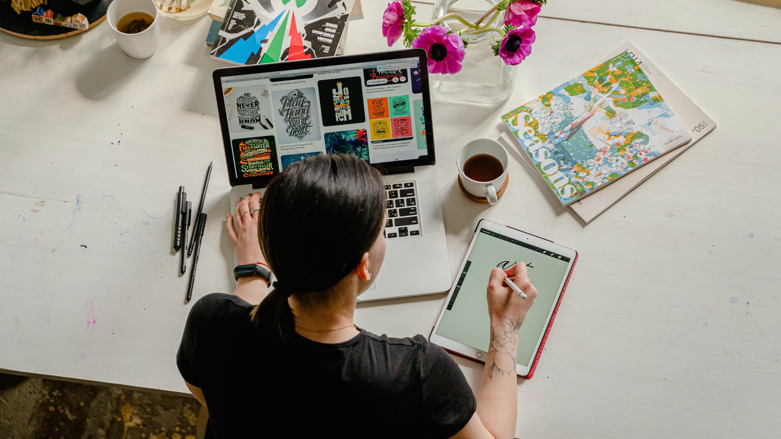 Person with laptop and drawing tablet on table with stylized text on both screens