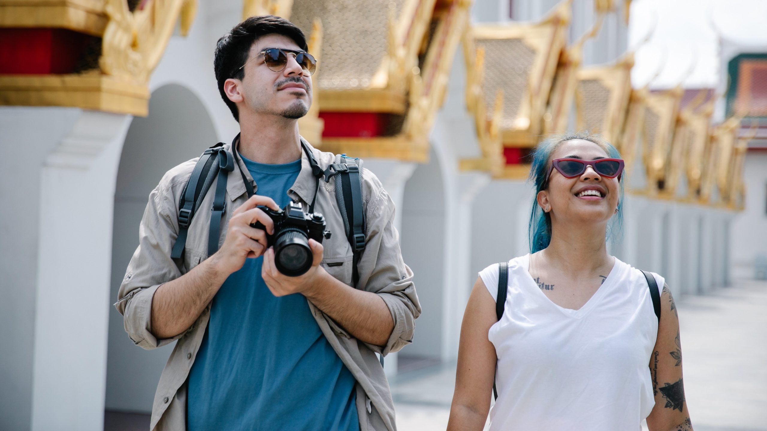 Two people sightseeing in sunglasses, one of them carrying a camera round their neck