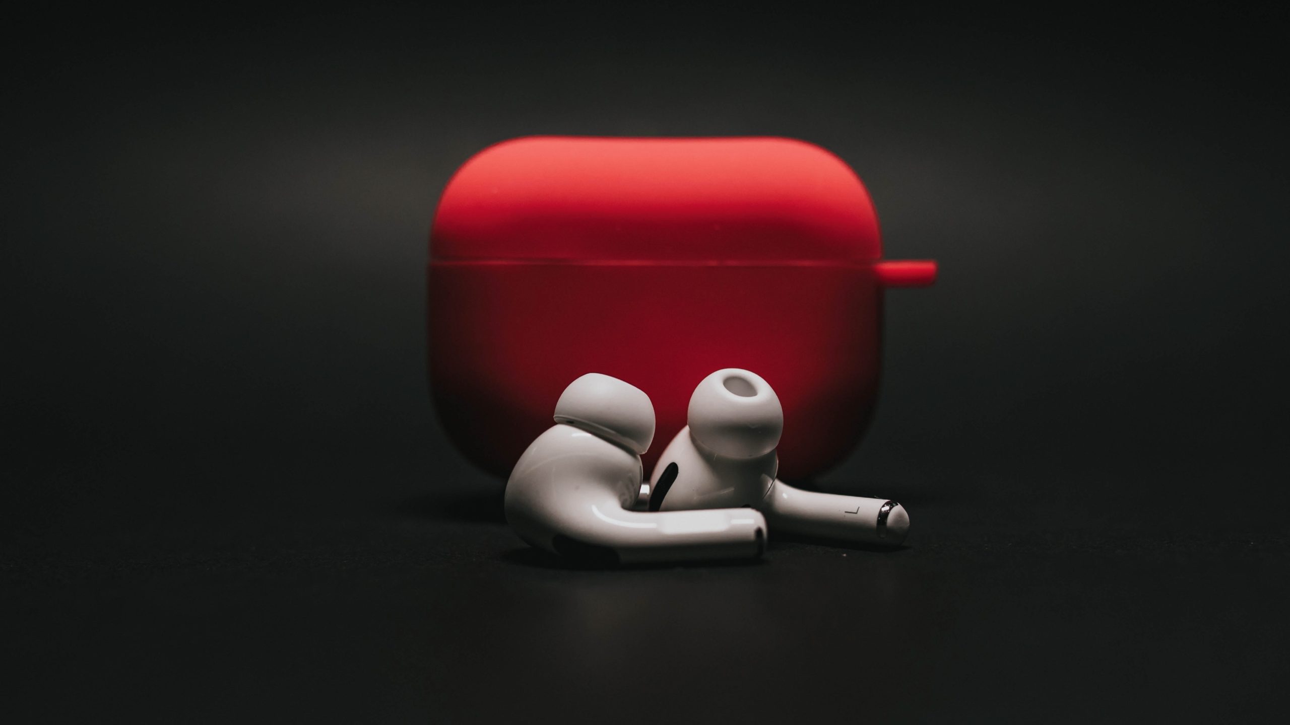White AirPods Pro in front of red case and black background