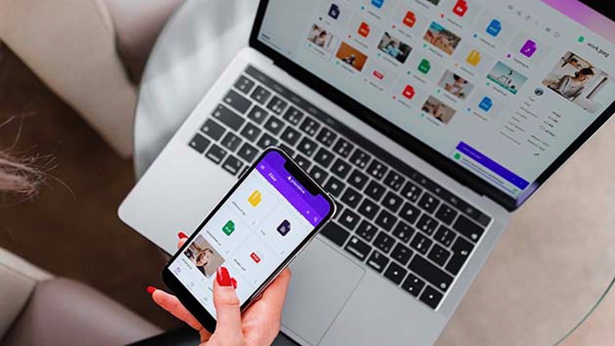 Hand holding phone in front of laptop