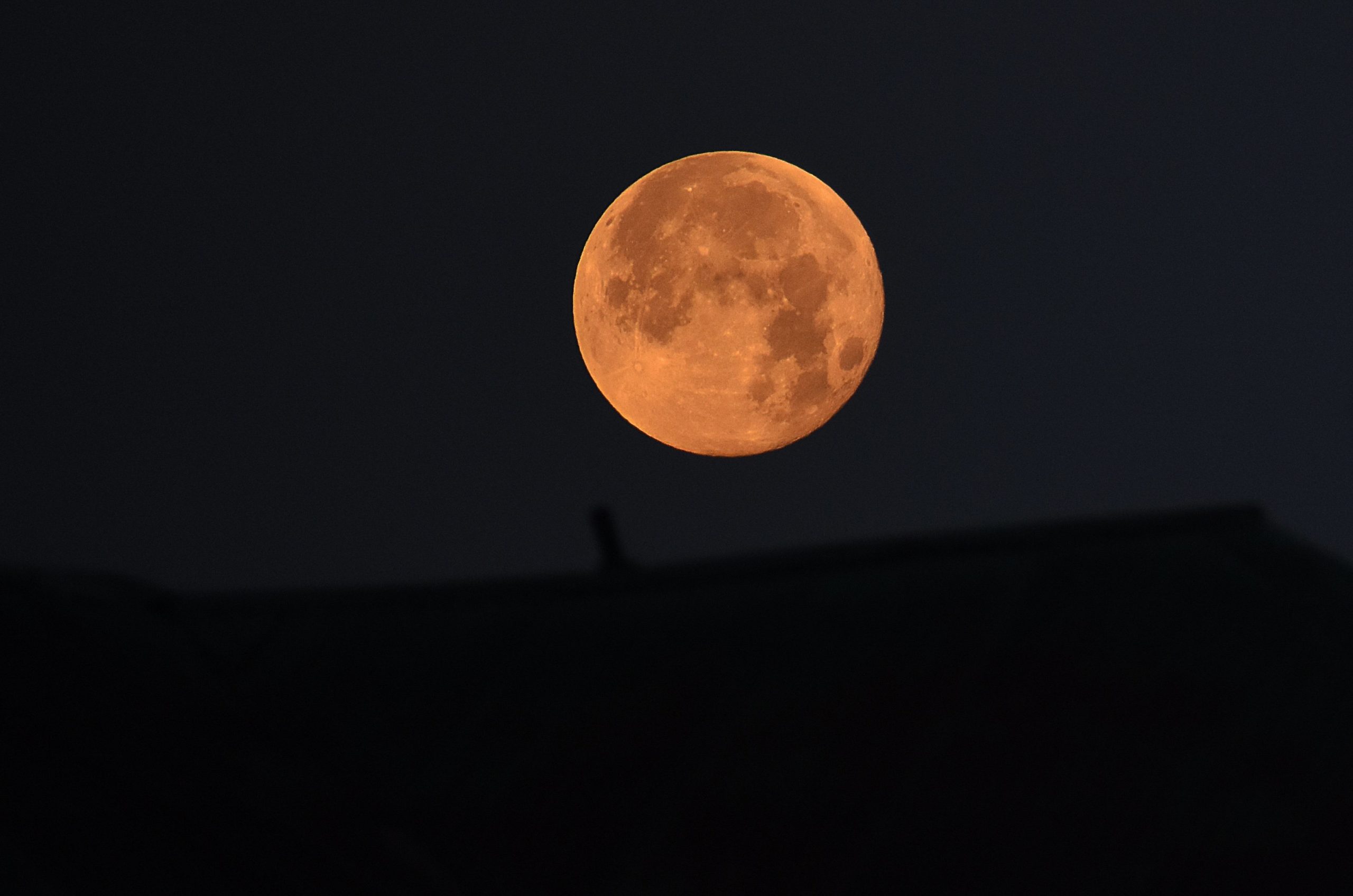 A lunar eclipse moon over a house. 