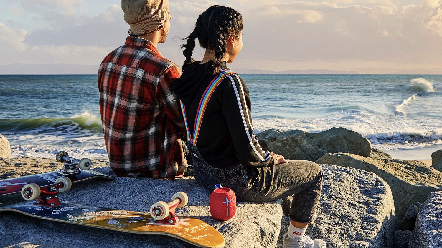 two people by the ocean with a skateboard and the red wonderboom speaker