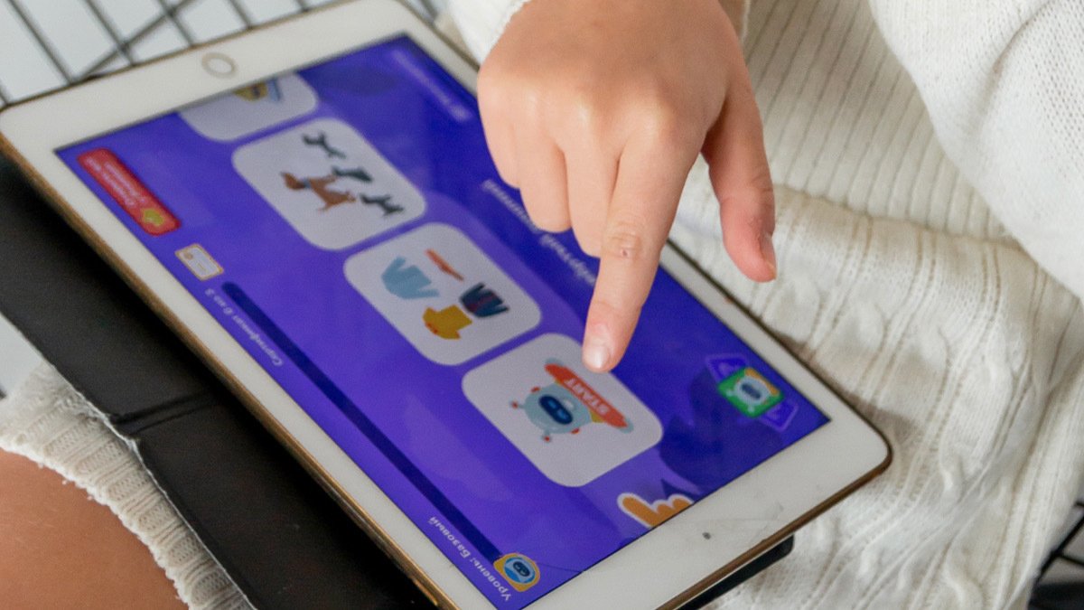 Finger poking ipad with learning game on screen