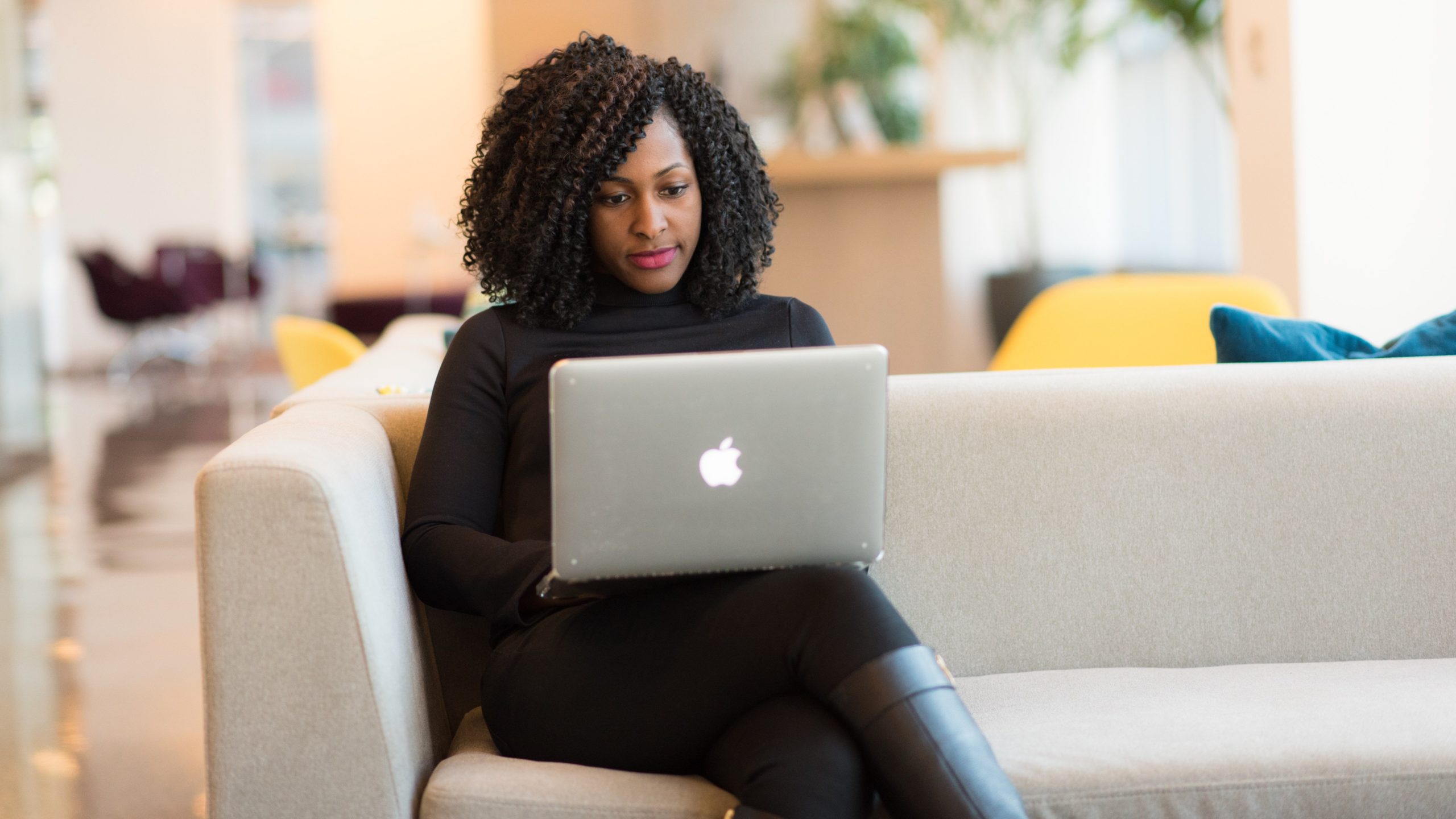 Woman Using Macbook Sitting on White Couch