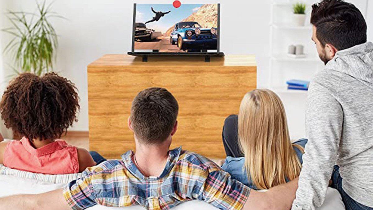 Four people on couch looking at projected image on wooden cabinet