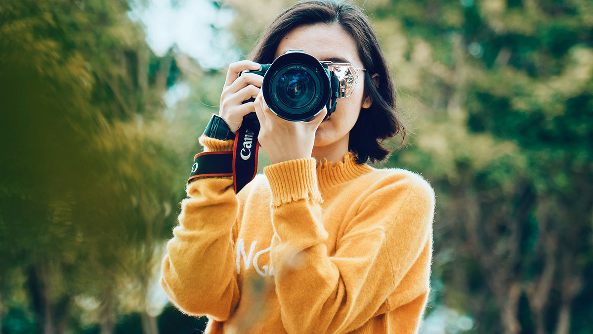 Person in orange sweater holding camera up to face