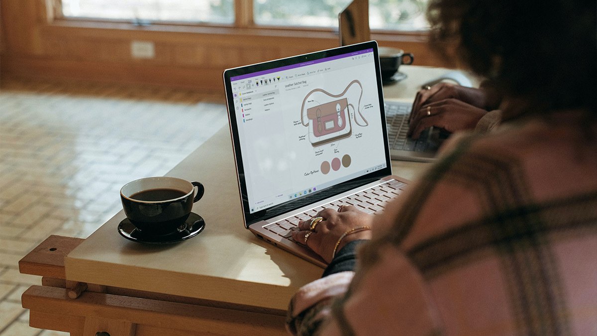 Person designing handbag on laptop at coffee table