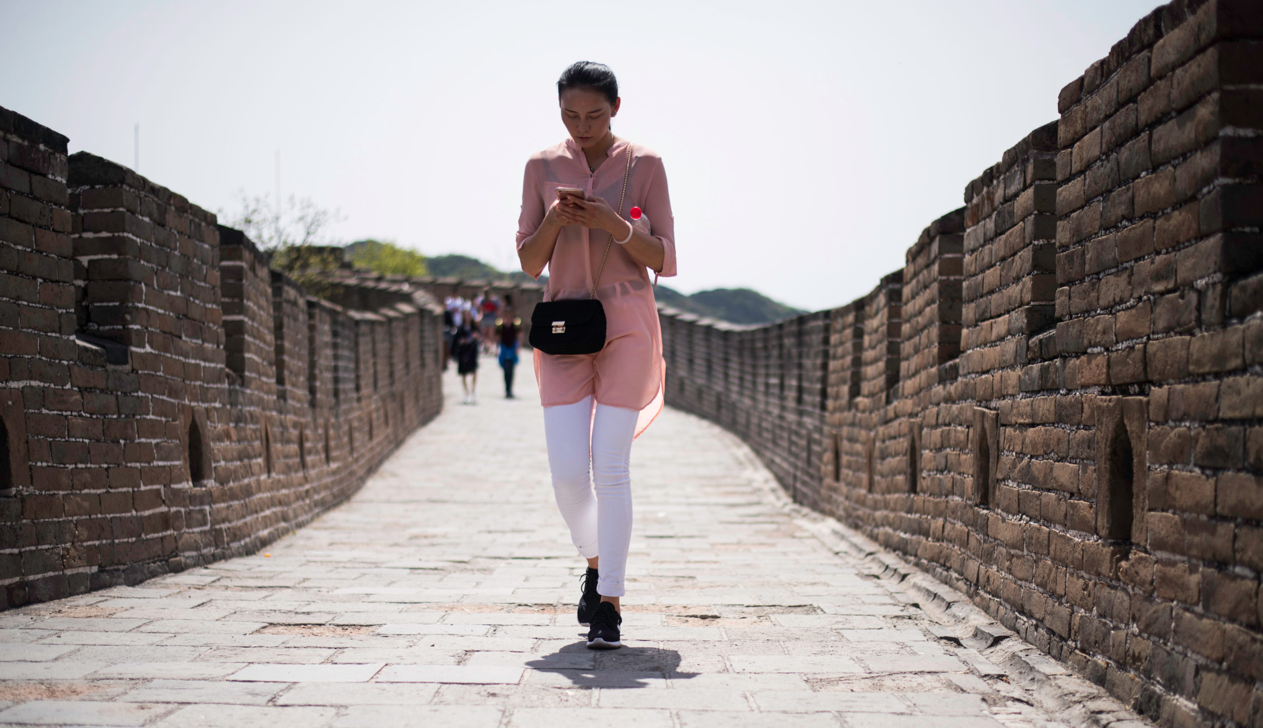 Woman holding a smart phone walks along the Great Wall in Mutianyu