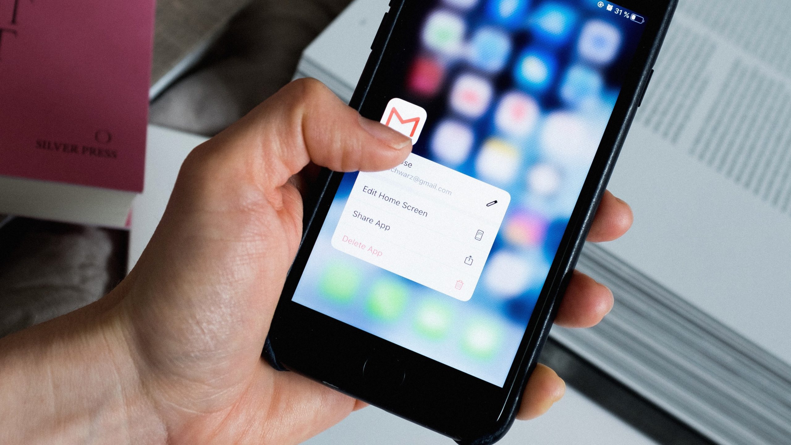 Hand holding phone showing gmail app in edit mode on home screen