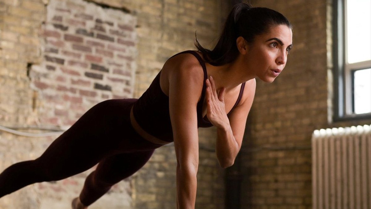 Person in plank position with one hand to shoulder