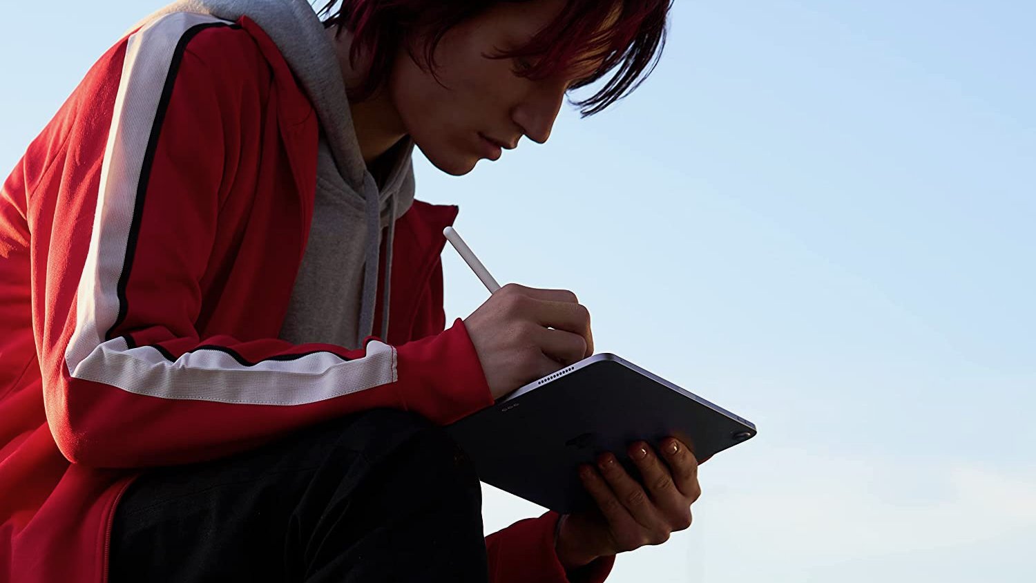 Person crouched over iPad using Apple Pencil with it