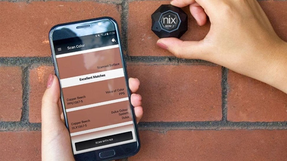 Black sensor held to a brown wall with a phone showing color match