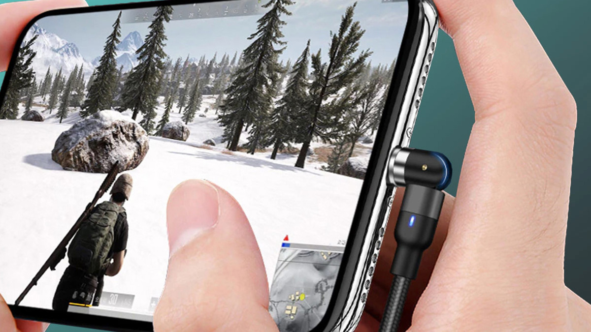 Hand holding plugged in phone showing game screen