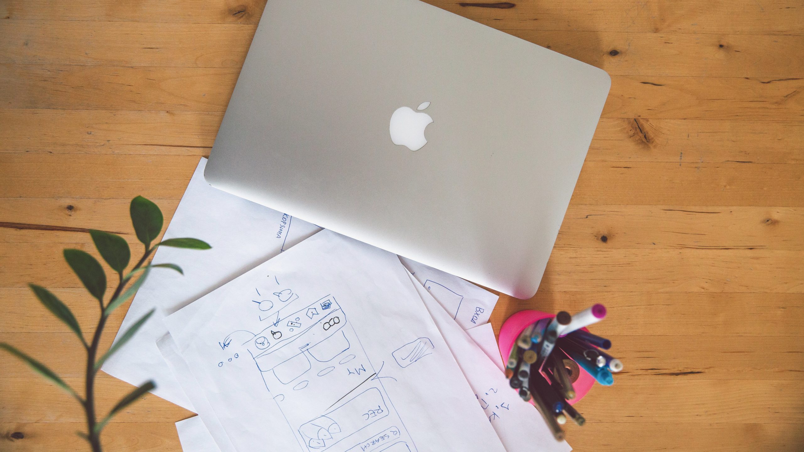 Silver macbook on wooden table with papers