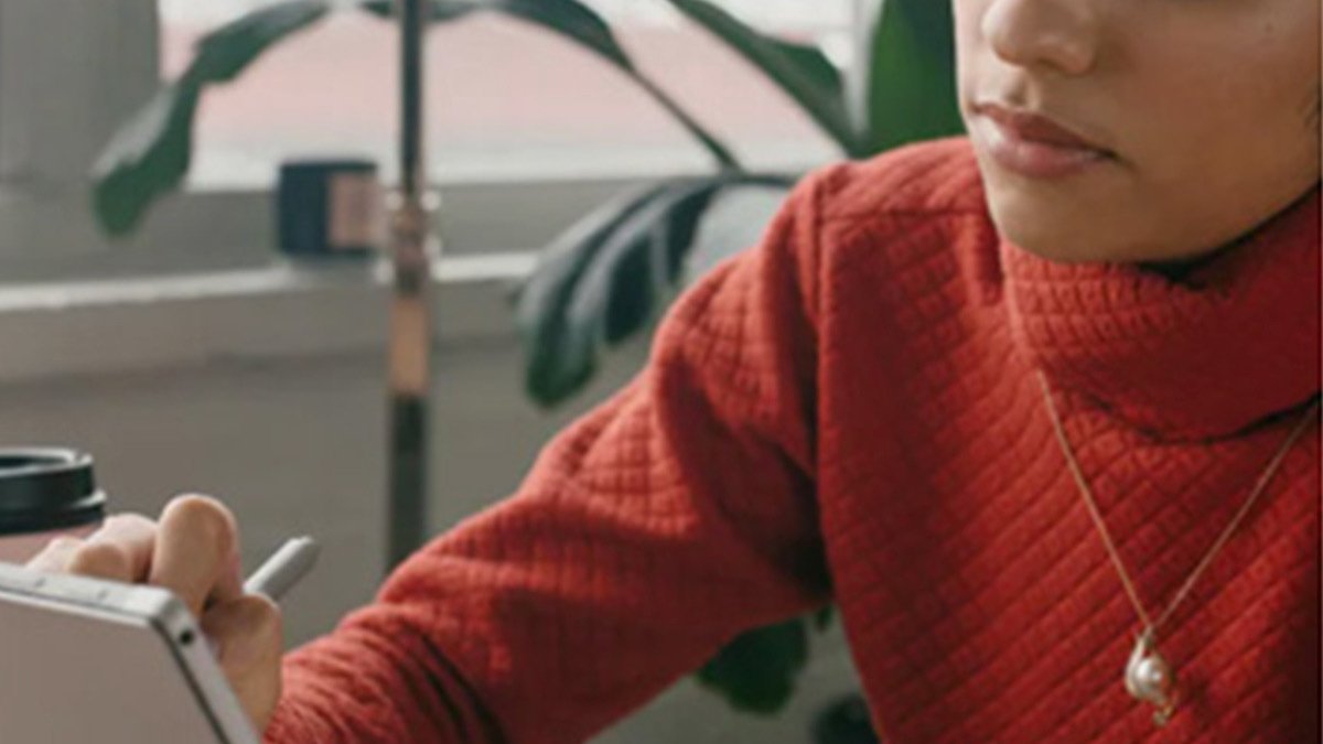 Person in orange sweater drawing on tablet