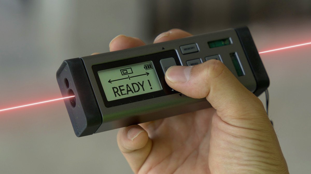 Black and grey rectangular distance measurer with red laser coming out of each end