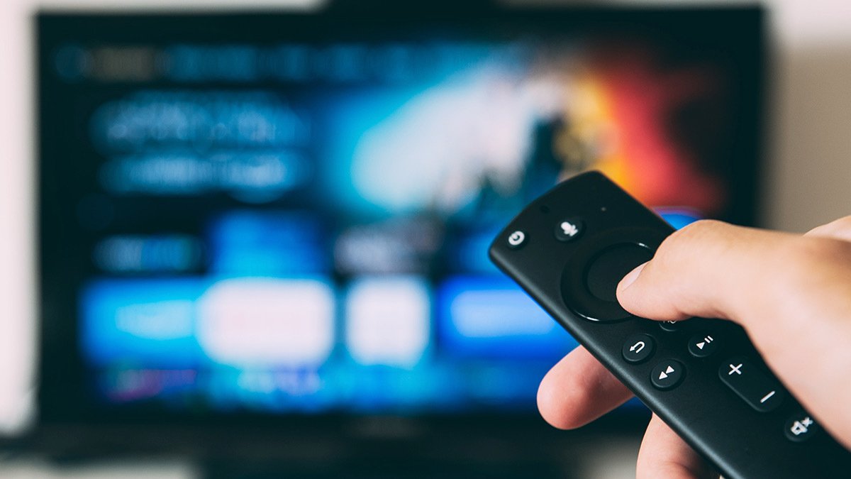 Hand holding remote pointed at TV