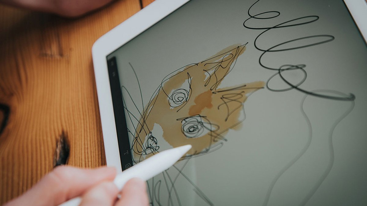 Hand holding white pen drawing fox on ipad