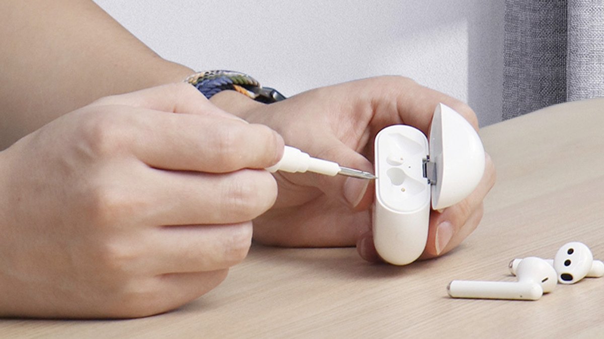 Hands using white pen to clean AirPods case