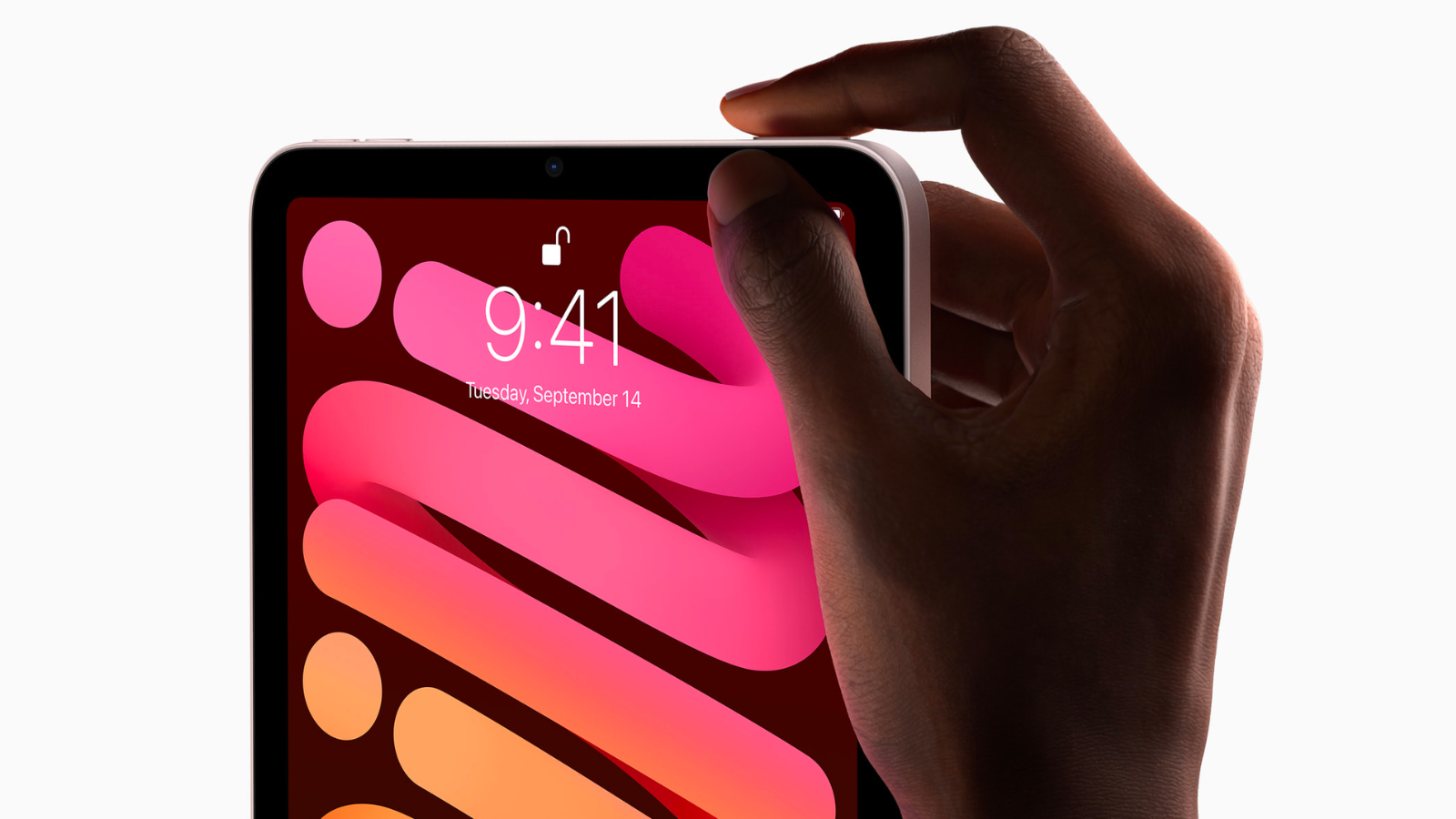 a hand holding the touch id button at the top of a pink apple ipad mini