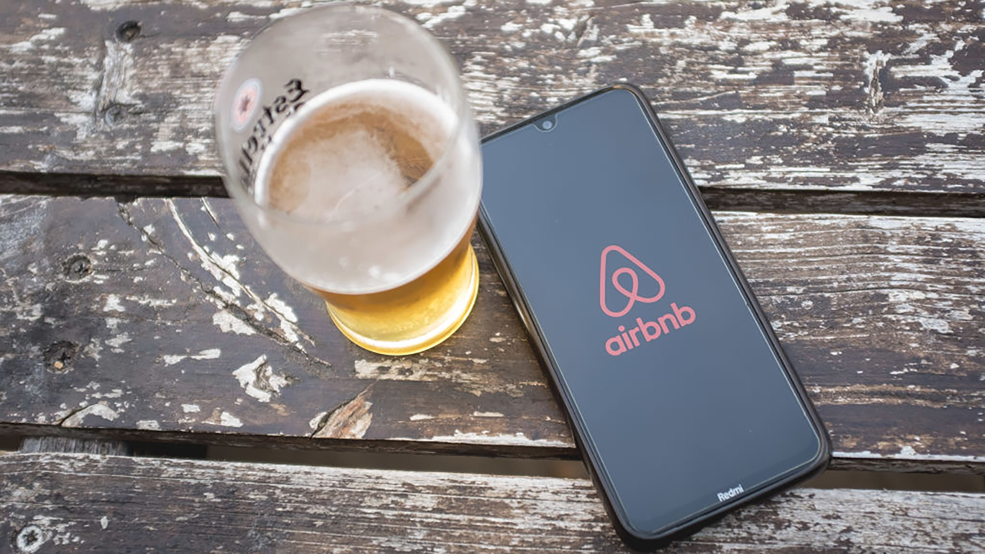 airbnb logo on phone next to beer on table