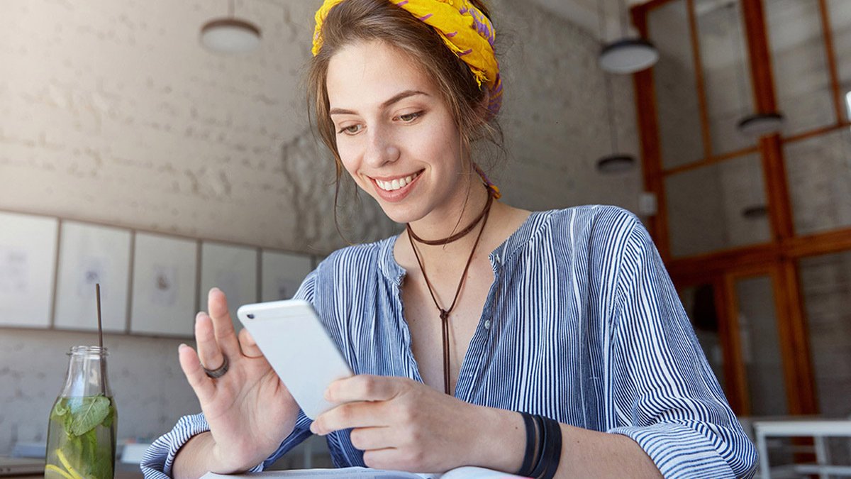 Person smiling at phone in front of textbooks