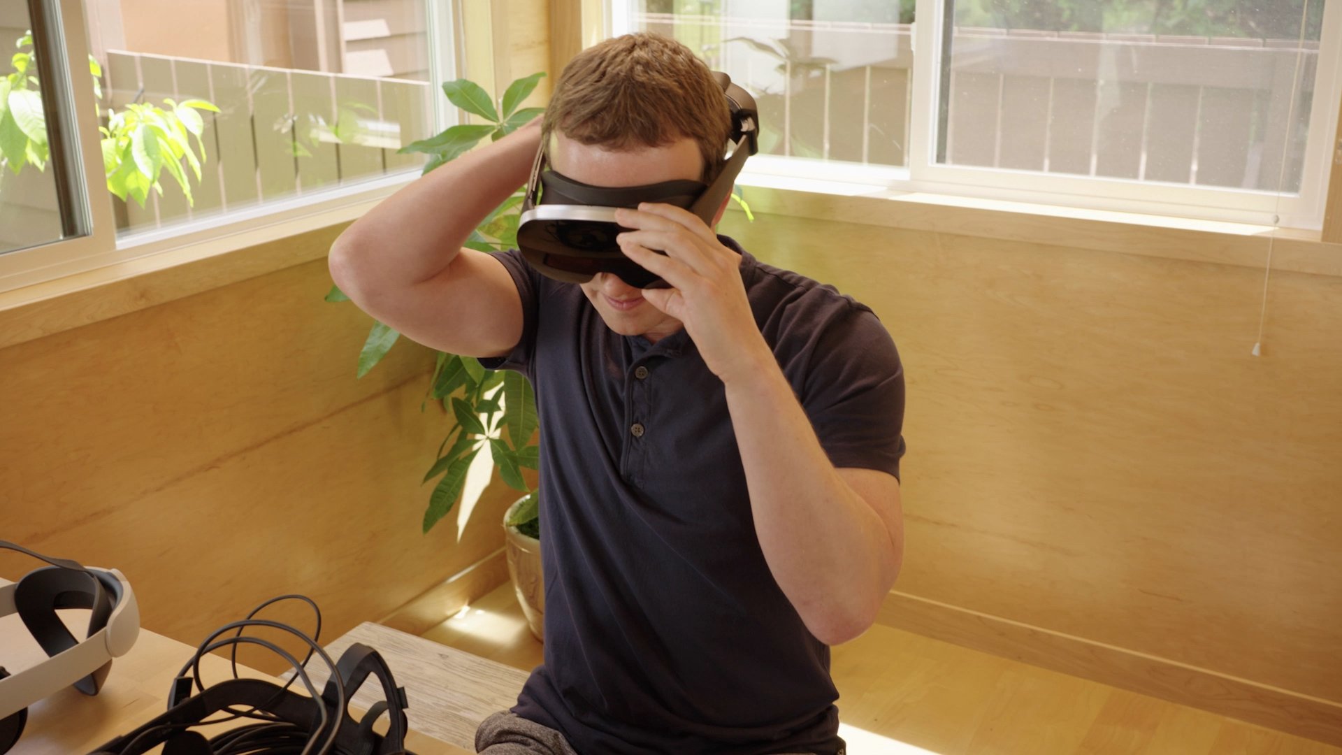 Zuckerberg sits on a bench with the Holocake 2 headset on.