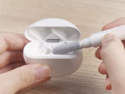 Hands using white pen to clean airpods case