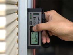 Hand holding distance measurer to wall with laser coming out of either end