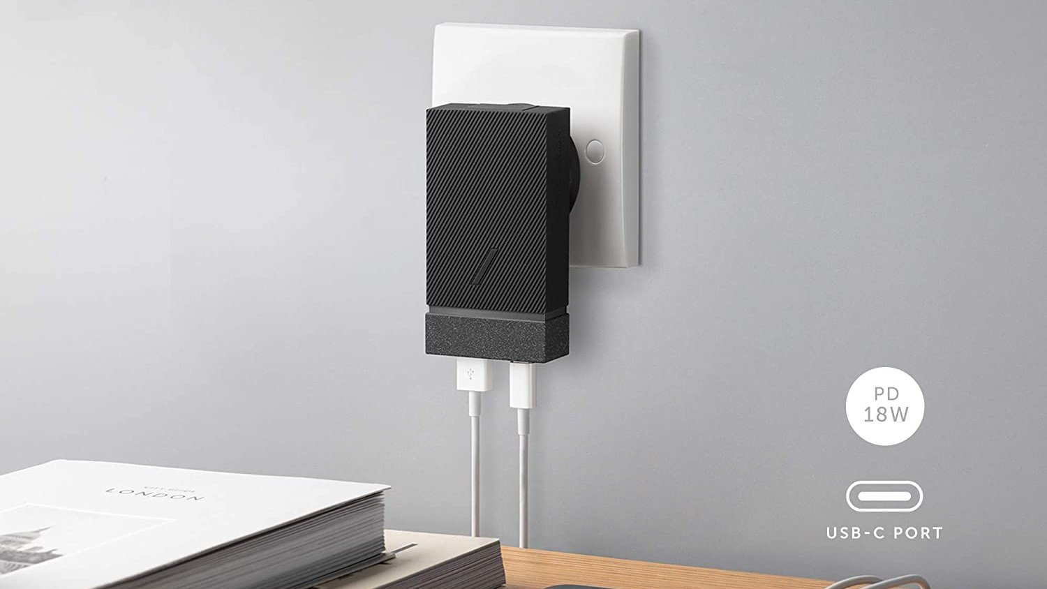 Black, rectangle shaped adapter plugged into the wall, with two white cords plugged into the bottom of it.